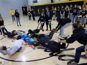 student on stomach collecting balls with bucket
