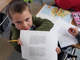 student holding paper to camera