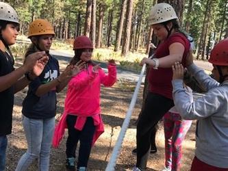 students helping other student through ropes course