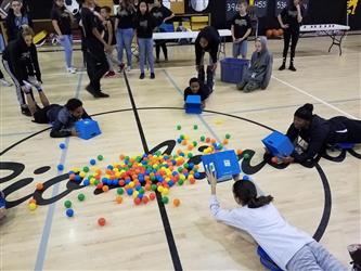 students on stomach collecting balls with buckets