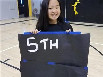 student holding 5th place sign