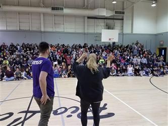people speaking to seated students in gym