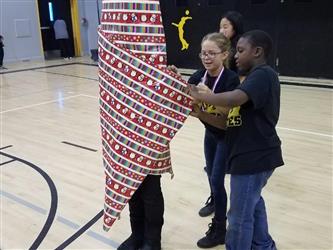 people wrapping student in gift wrap