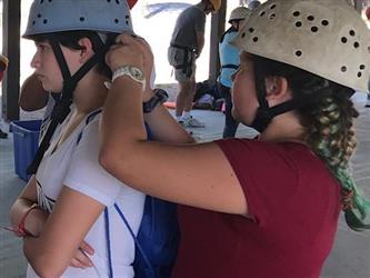 student putting helmet on other student