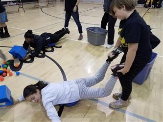 student on stomach collecting balls with bucket