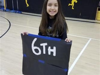 student holding 6th place sign